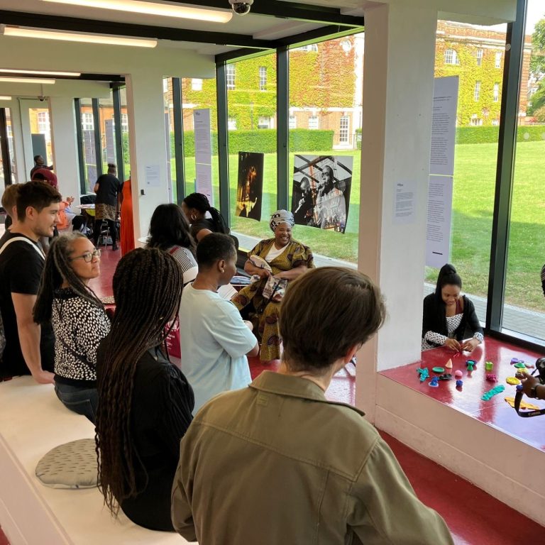 A group of people engaged in an art exhibition in a bright gallery space.