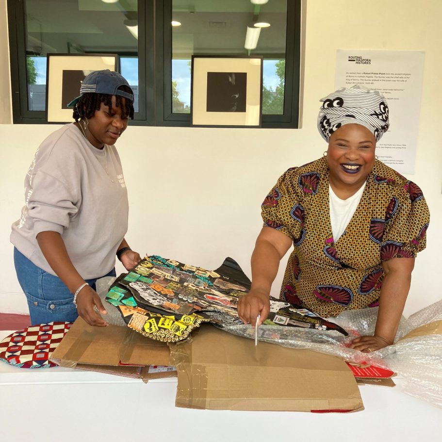 Two women unpacking artwork on a table in a bright room.